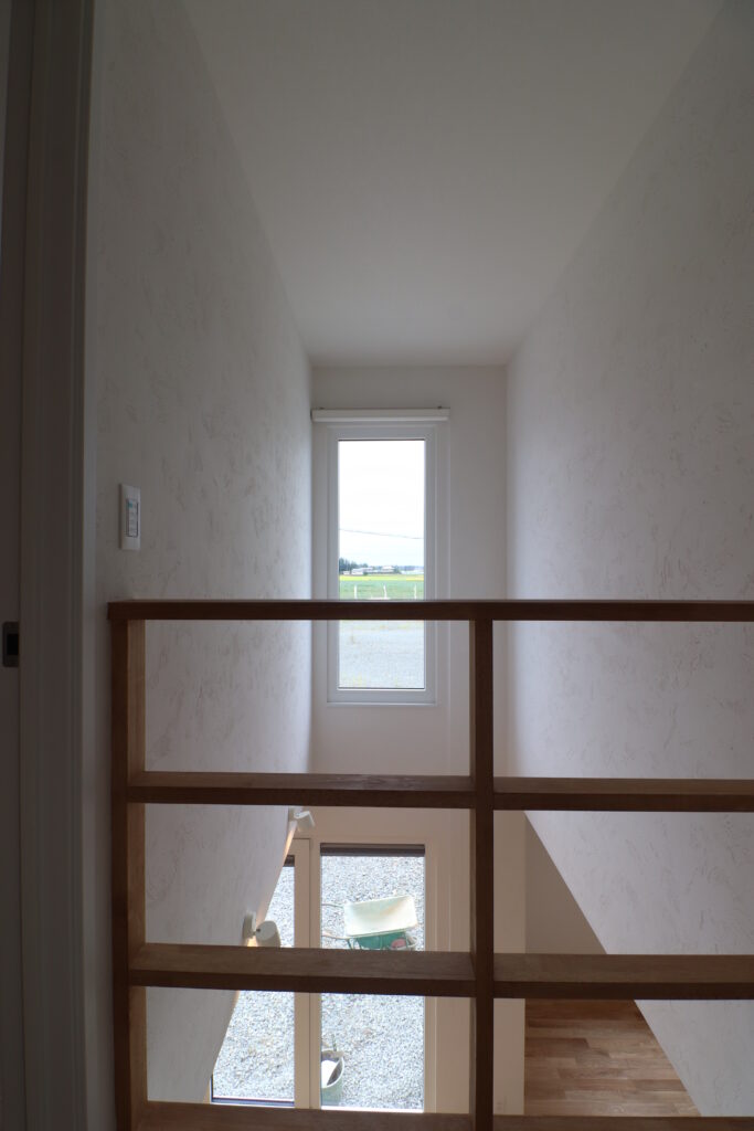 2階の手すりから吹き抜け窓と屋外の景色を見下ろす吹き抜け空間の画像
