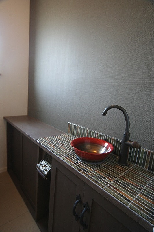 モザイクタイル仕上げのカウンターに赤の手洗いボウルとアンティーク水栓を設置したトイレ手洗いの画像