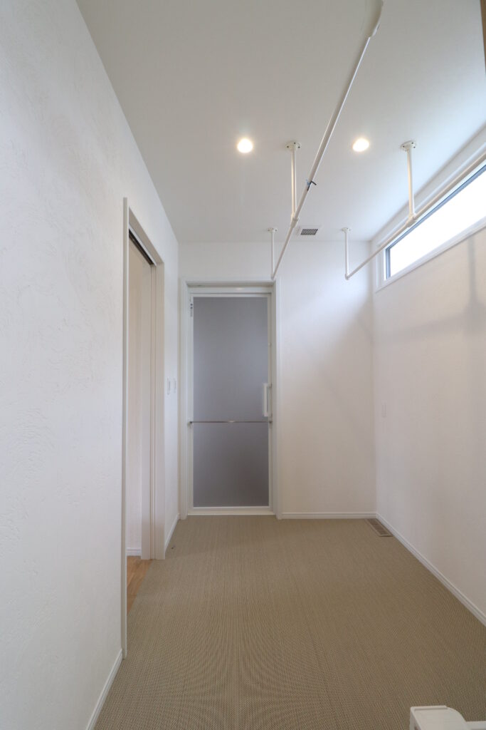 室内物干しパイプが設置された明るく清潔感のある脱衣室の画像