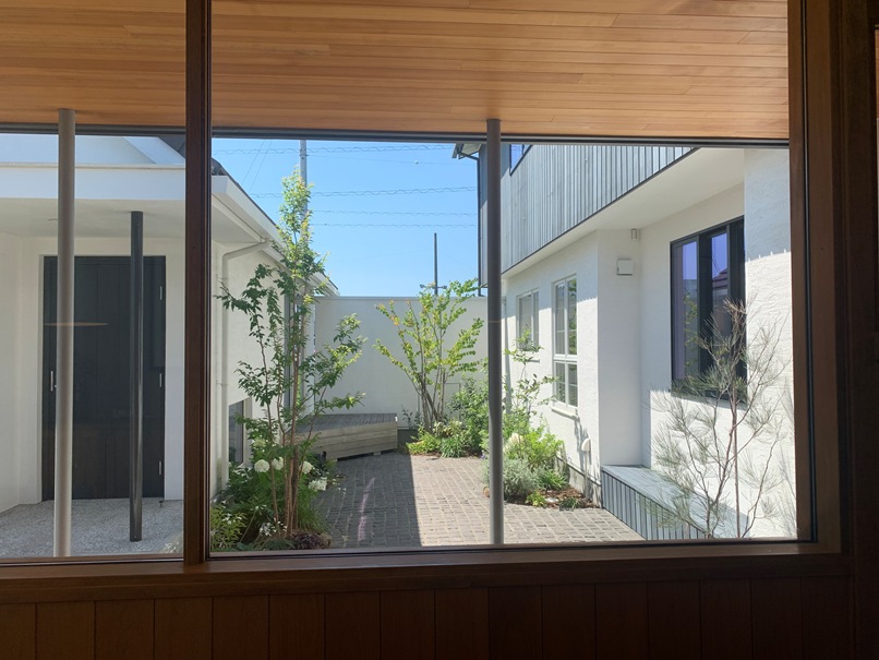 リビングの窓越しに見る中庭。建物が庭を囲むコートハウス型の画像